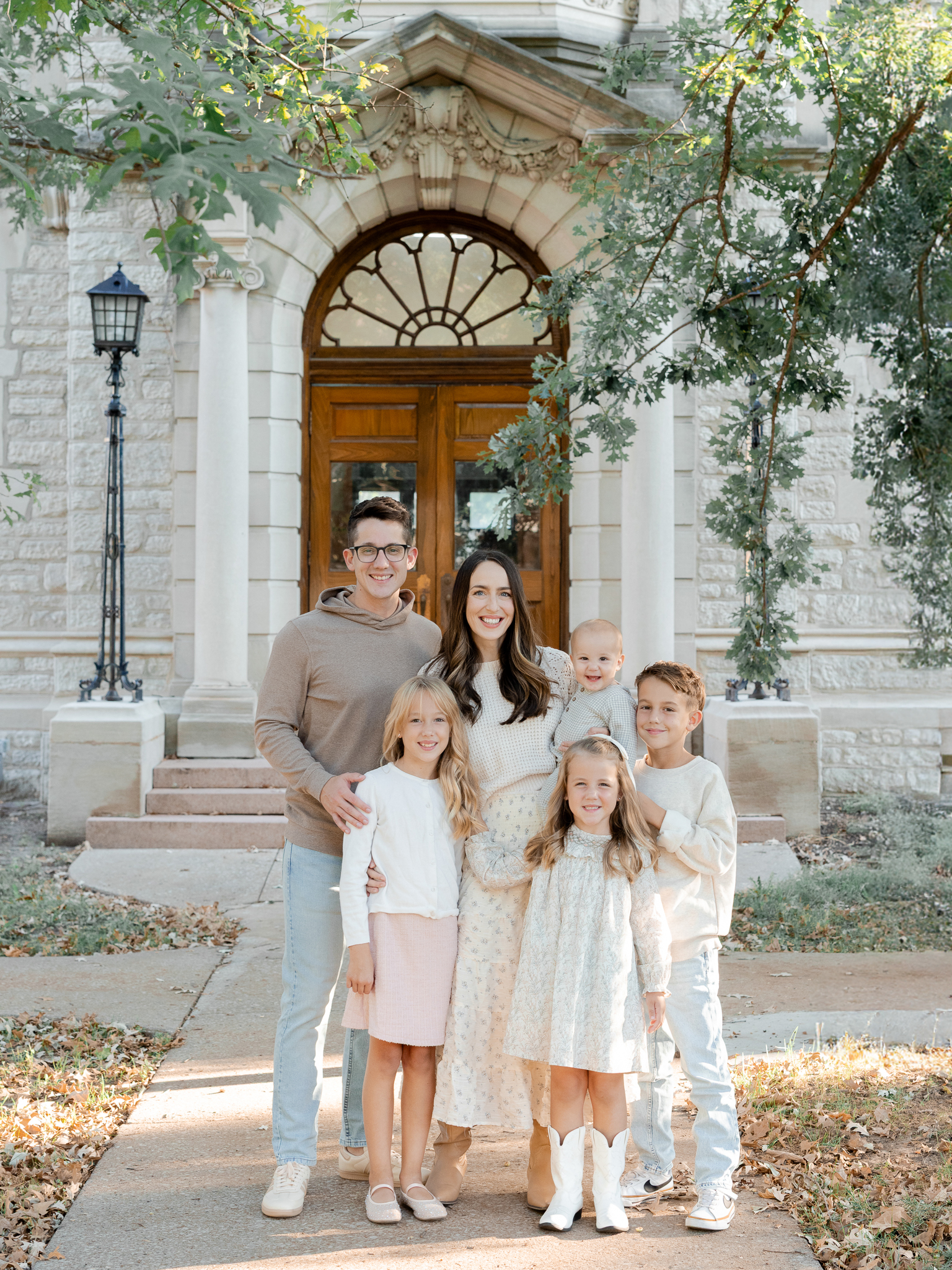 The Bedford family of six smiling together in front of an arched doorway, photographed by Columbia Missouri family photographer Love Tree Studios.
