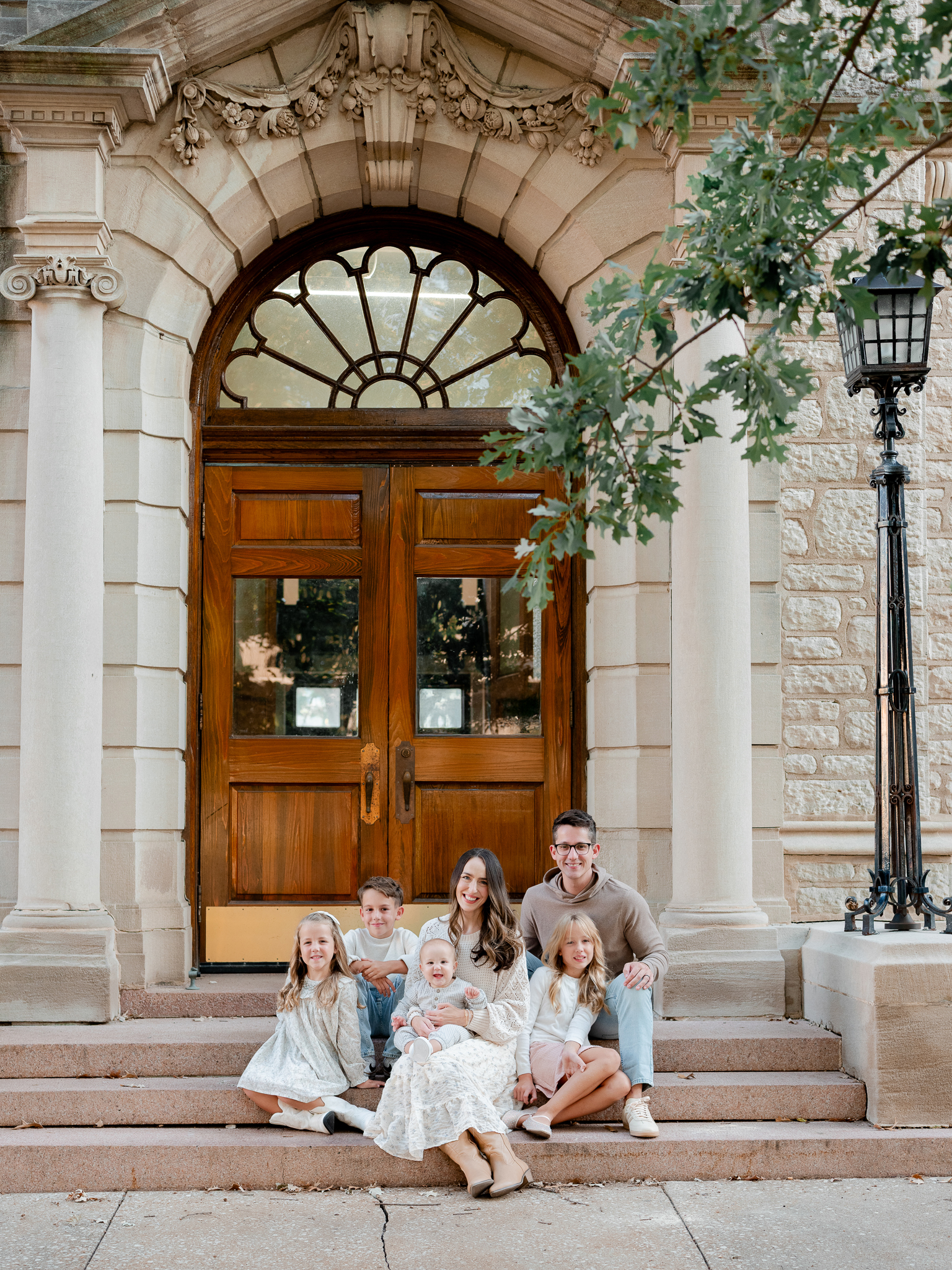 The Bedford family of six gathered on steps in front of a grand wooden doorway, photographed by Love Tree Studios, Columbia Missouri family photographer.