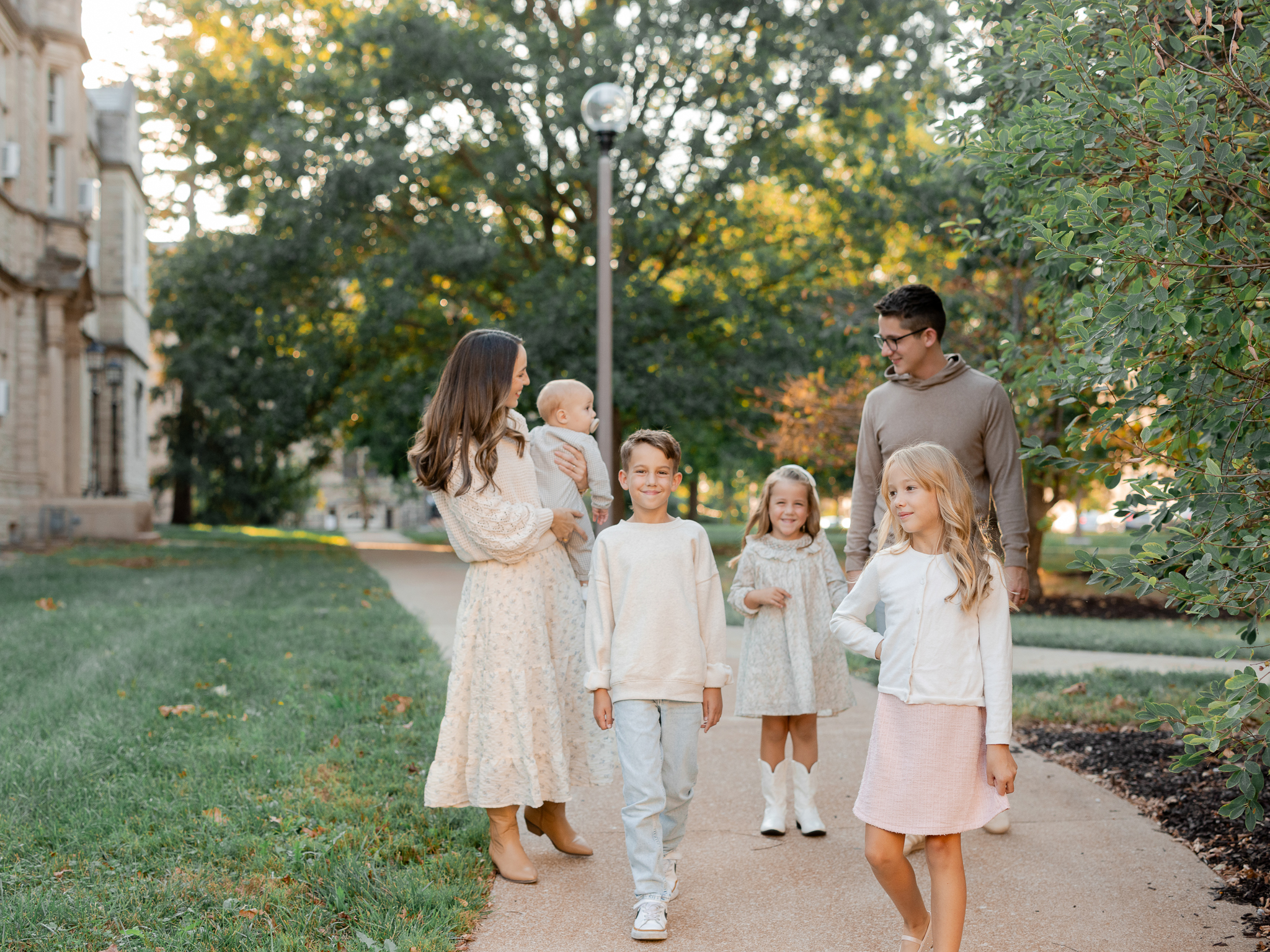 Parents and children walking on a leafy campus path at golden hour, photographed by Love Tree Studios, Columbia Missouri family photographer.