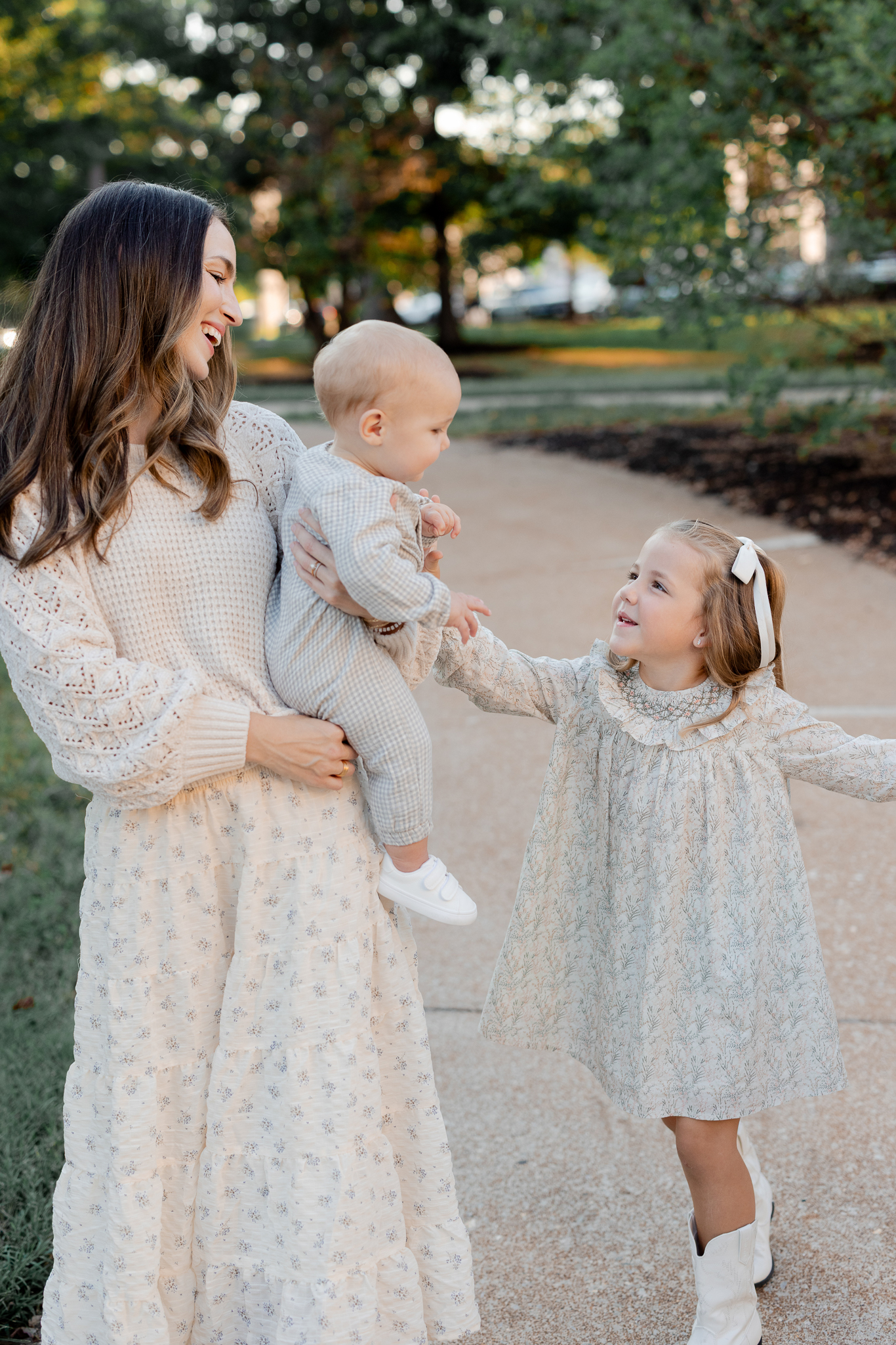 Mom holding her baby as her daughter reaches up with a smile during a Columbia Missouri family session with Love Tree Studios.