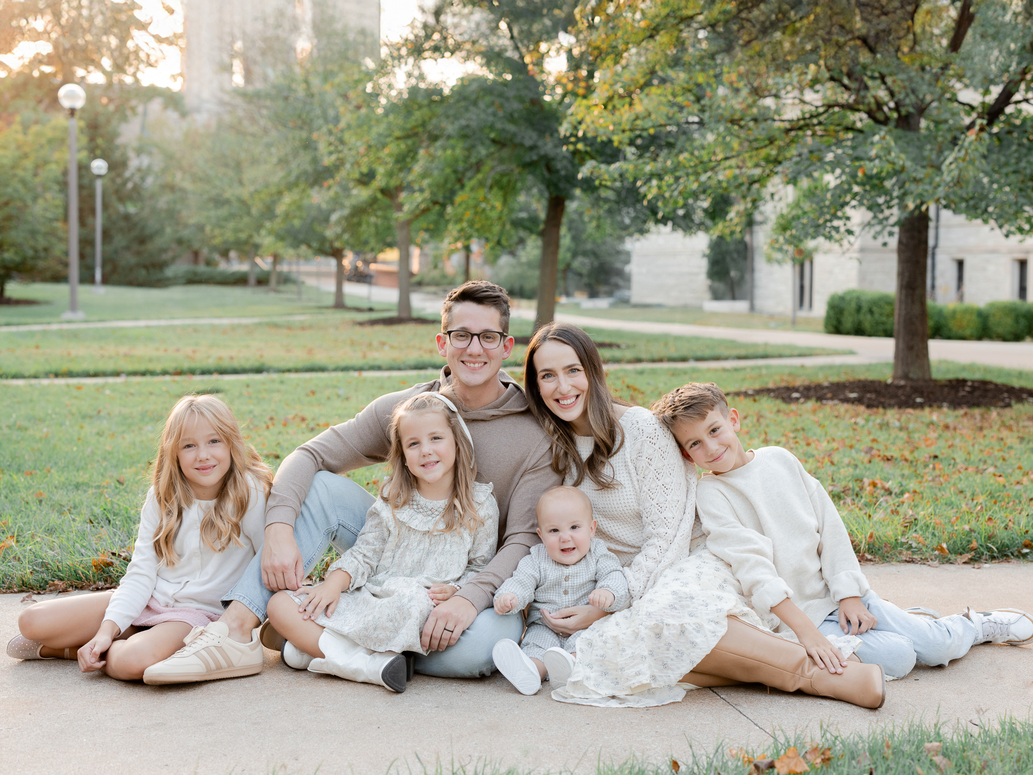 Bedford family sitting together in the grass, laughing and enjoying a golden hour session in Columbia, Missouri by Love Tree Studios.