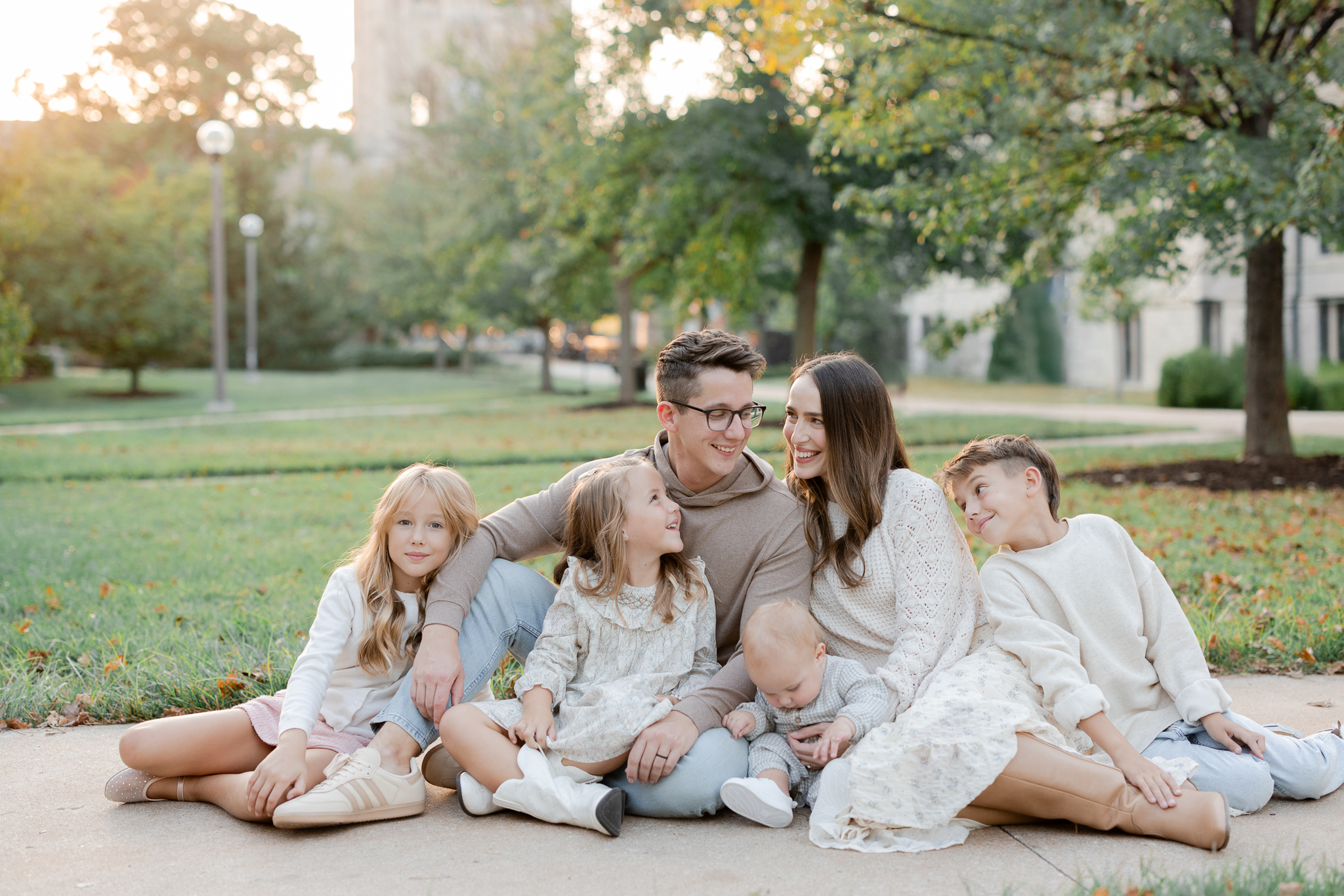 Family of six sitting close together in a Columbia park at sunset, captured by Columbia Missouri family photographer.