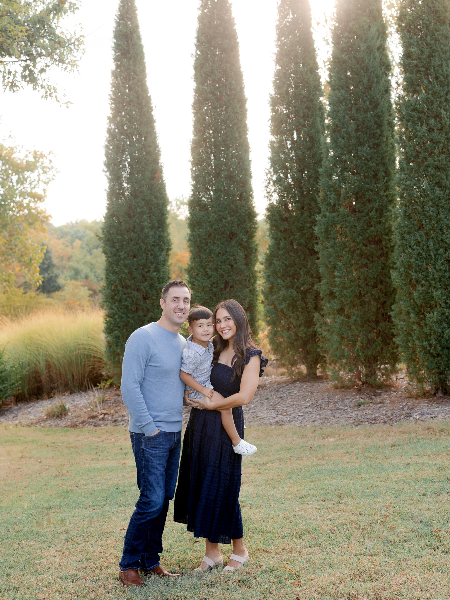 Parents holding their son in golden morning light at Stephens Lake Park, captured by Love Tree Studios.