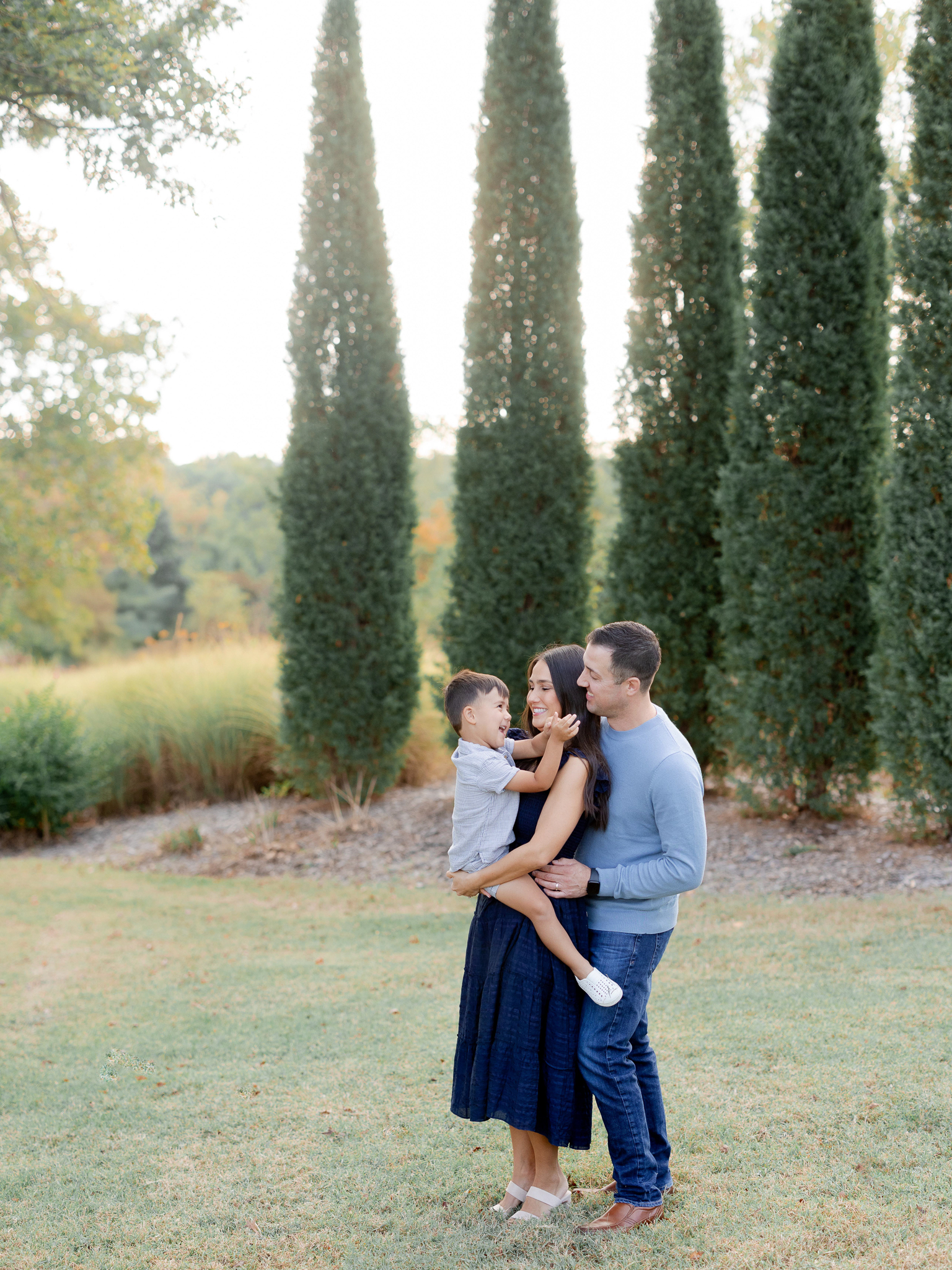 Family of three standing together at Stephens Lake Park during a fall morning session with Columbia Missouri photographer Love Tree Studios