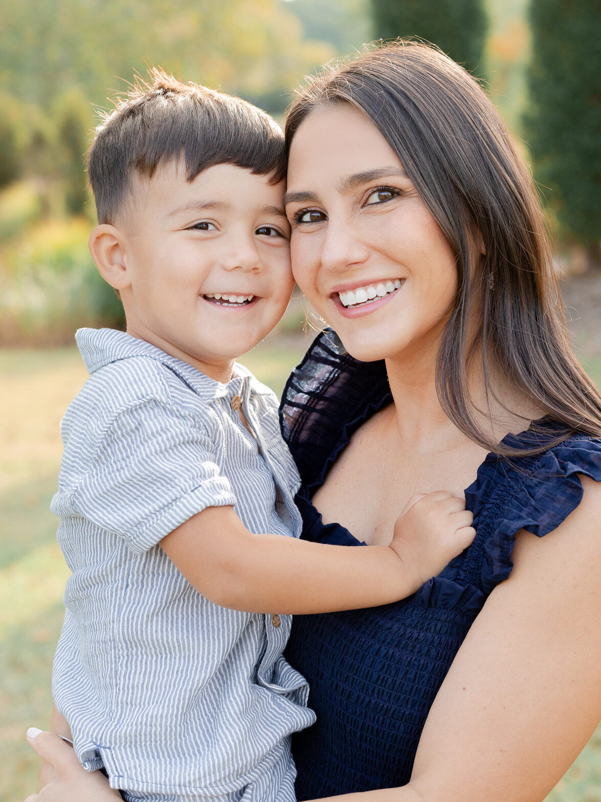 Mom holding son and smiling at the camera during a fall morning photo shoot in Columbia Missouri.