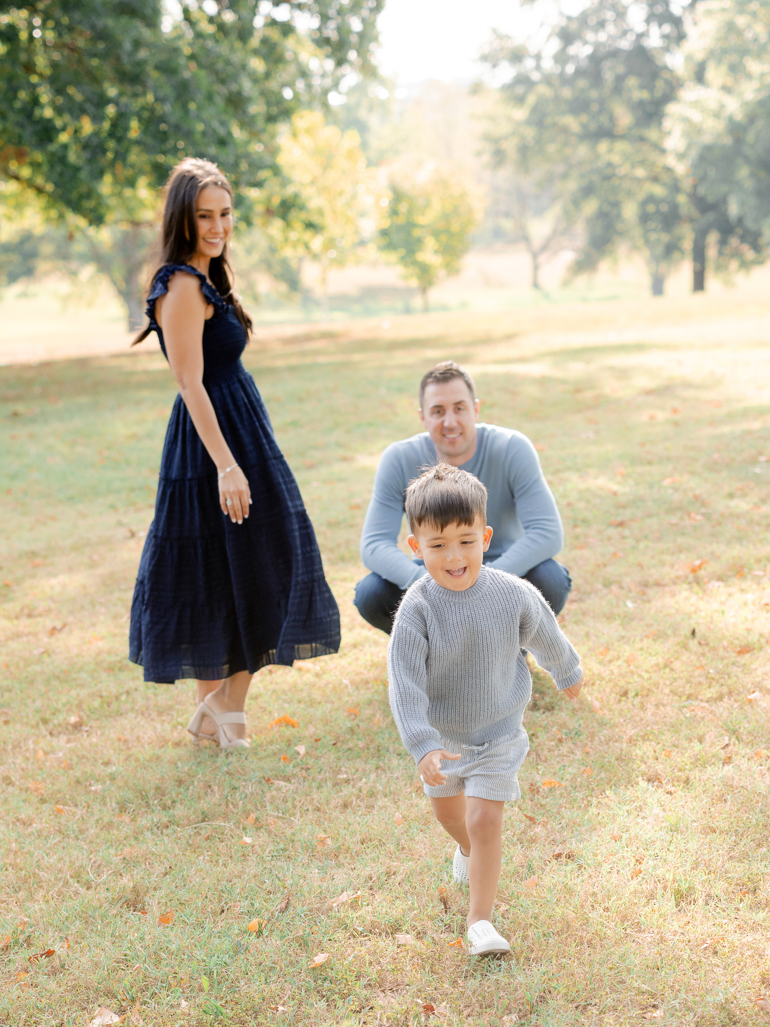 Little boy running in front of his parents, smiling brightly during a Columbia Missouri family session.