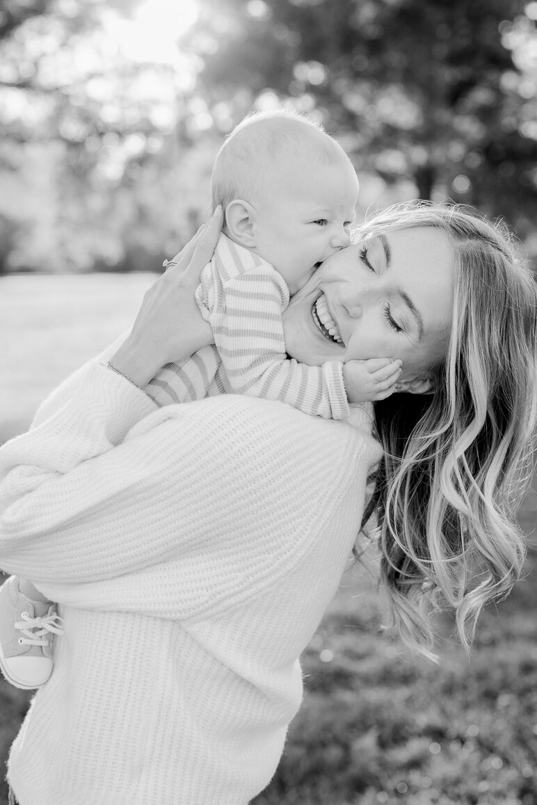 A mother laughing as her baby cuddles her face during a black and white portrait, captured by Love Tree Studios for golden sunset family photos in Columbia, MO.