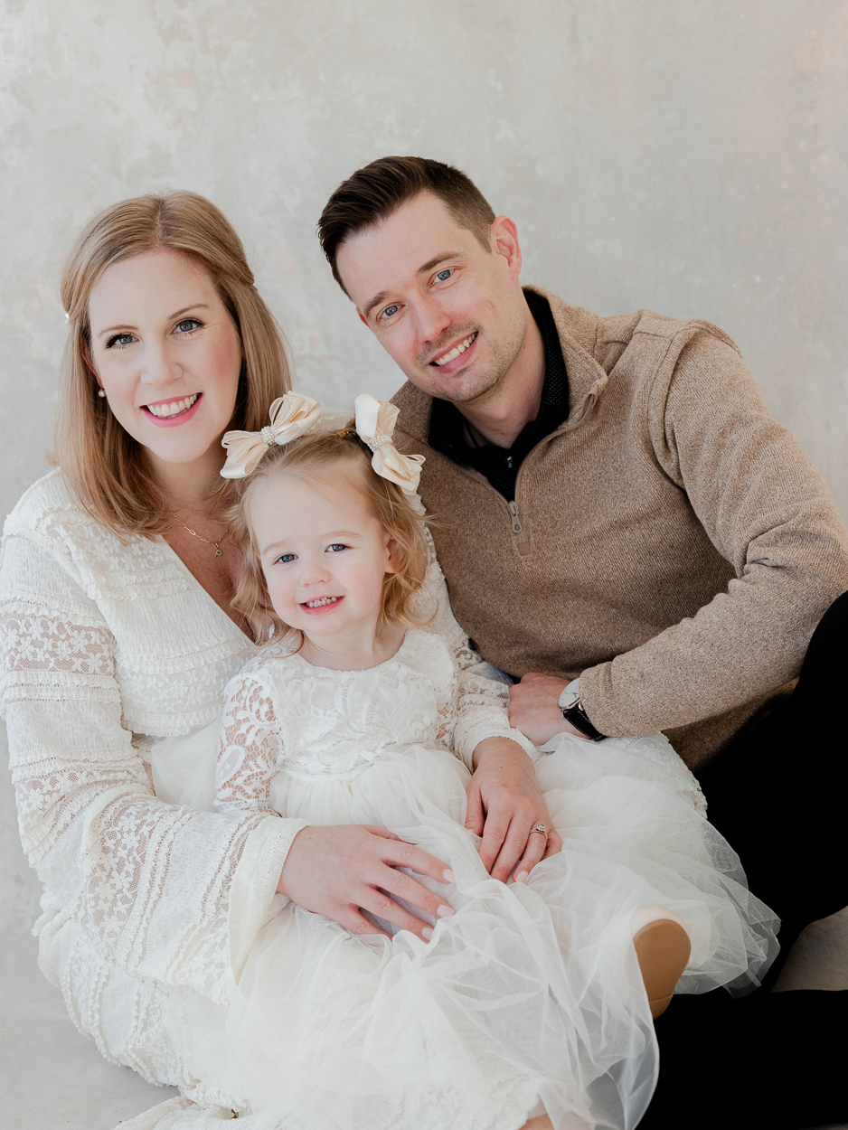 Close up family portrait with parents and toddler daughter in natural light studio in Columbia Missouri.