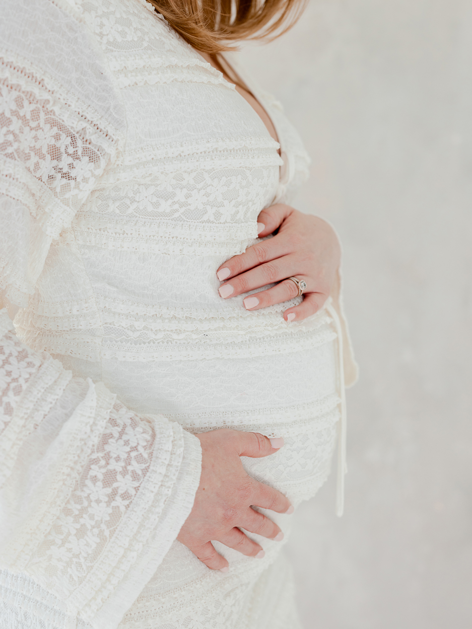 Close up detail of mother’s hands on baby bump during Columbia Missouri studio maternity session.
