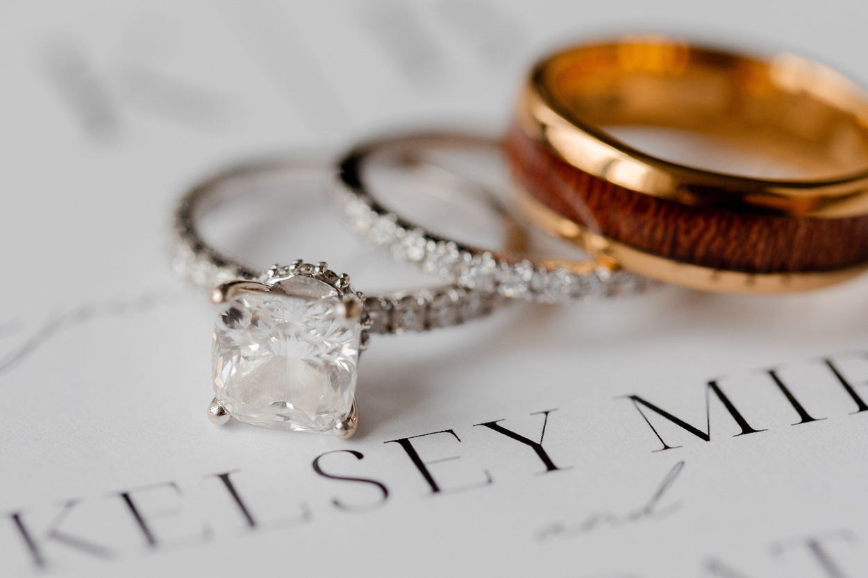 Close-up of engagement ring and wedding bands styled on wedding invitation for a Columbia Missouri church wedding.