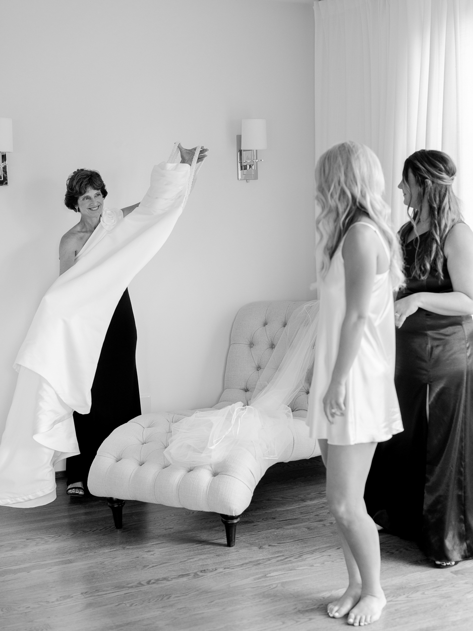 Mother holding the bride’s wedding dress while bridesmaids look on before a Columbia Missouri church wedding.