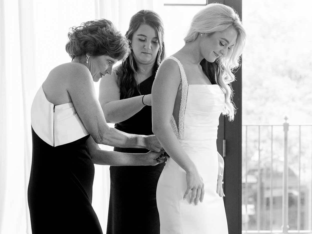 Black and white photo of bride getting ready with her mother and bridesmaid before her Columbia Missouri church wedding.
