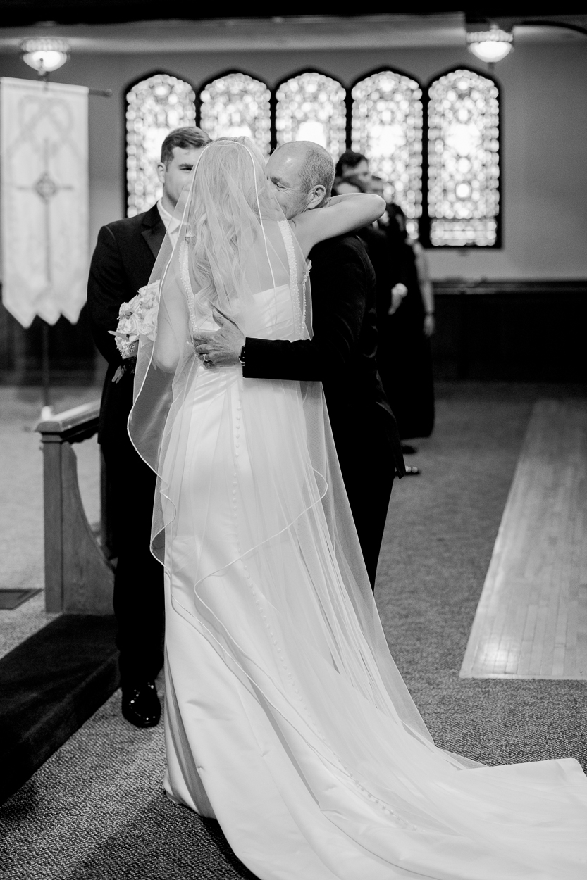 Bride hugging her father at the altar during an emotional moment at their Columbia Missouri church wedding.