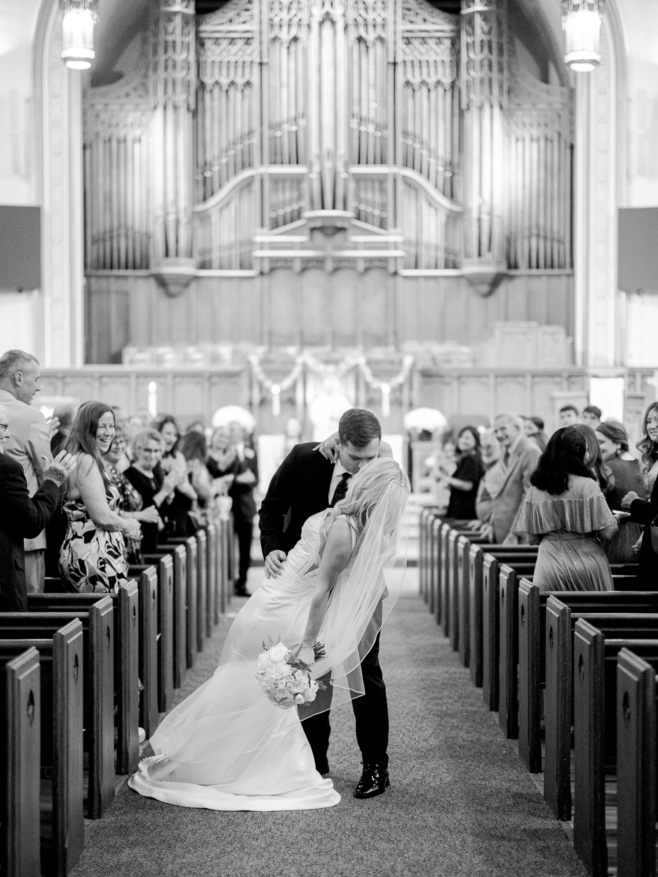 Bride and groom dipping for a celebratory kiss in the church aisle after their Columbia Missouri church wedding ceremony.