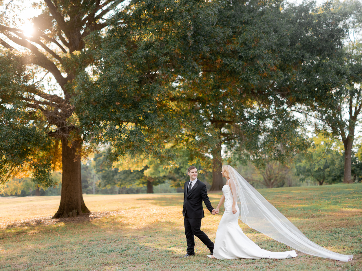 Bride and groom walking hand in hand at Stephens Lake Park during golden hour portraits at their Columbia Missouri church wedding.
