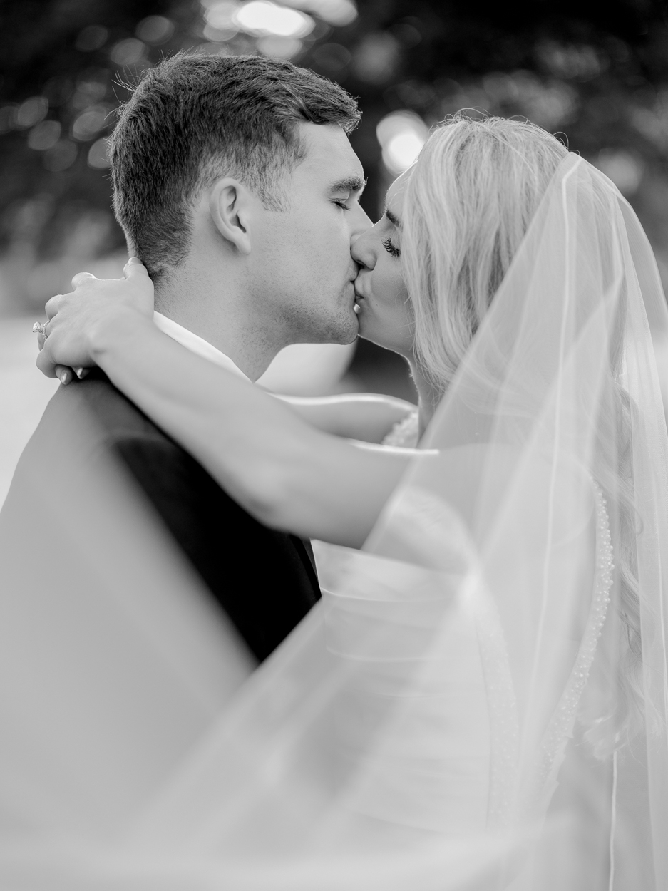 Black and white portrait of the bride and groom kissing during golden hour after their Columbia Missouri church wedding.