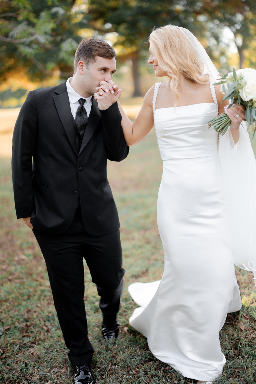 Groom kissing the bride’s hand during romantic golden hour portraits following a Columbia Missouri church wedding.