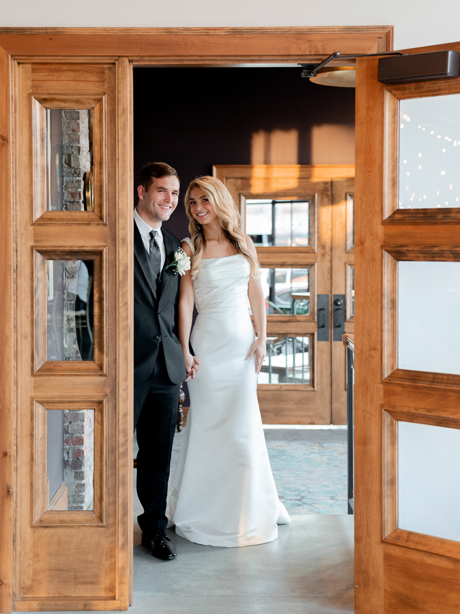 Bride and groom framed in wooden doors inside The Atrium on Tenth following their Columbia Missouri church wedding.