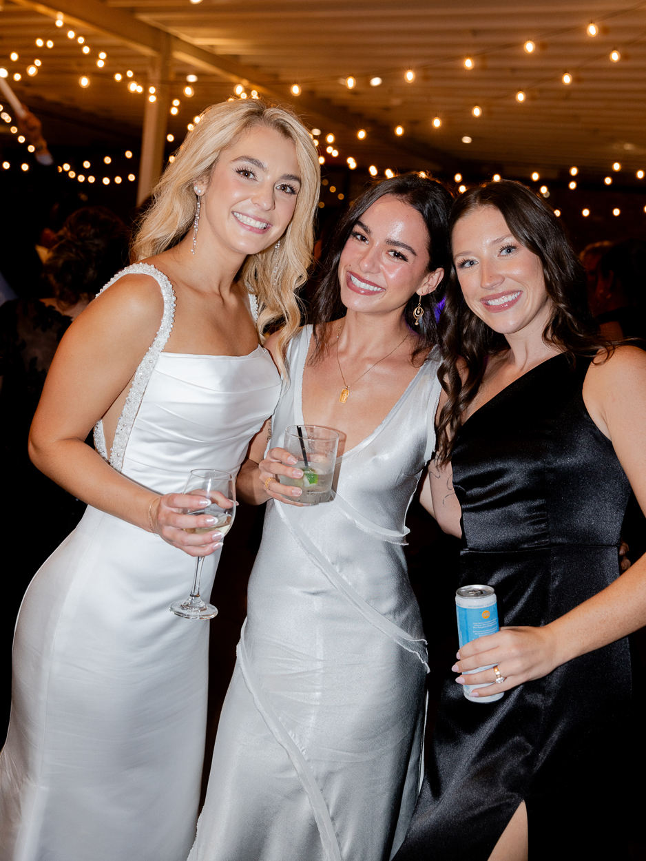 Bride celebrating with friends on the dance floor under twinkle lights at her Columbia Missouri church wedding reception.