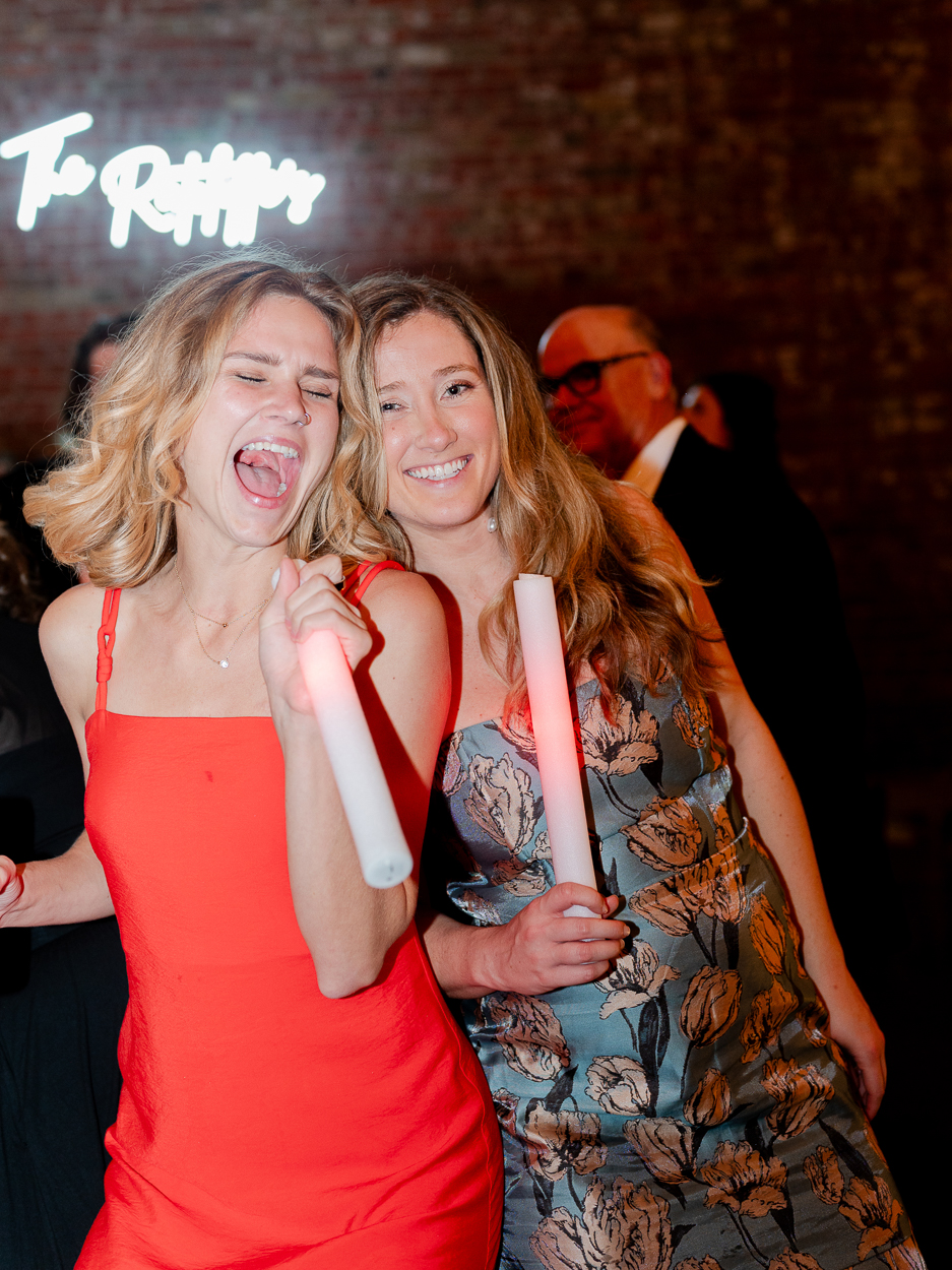 Wedding guests dancing and laughing with glow sticks during the reception in Columbia, Missouri.