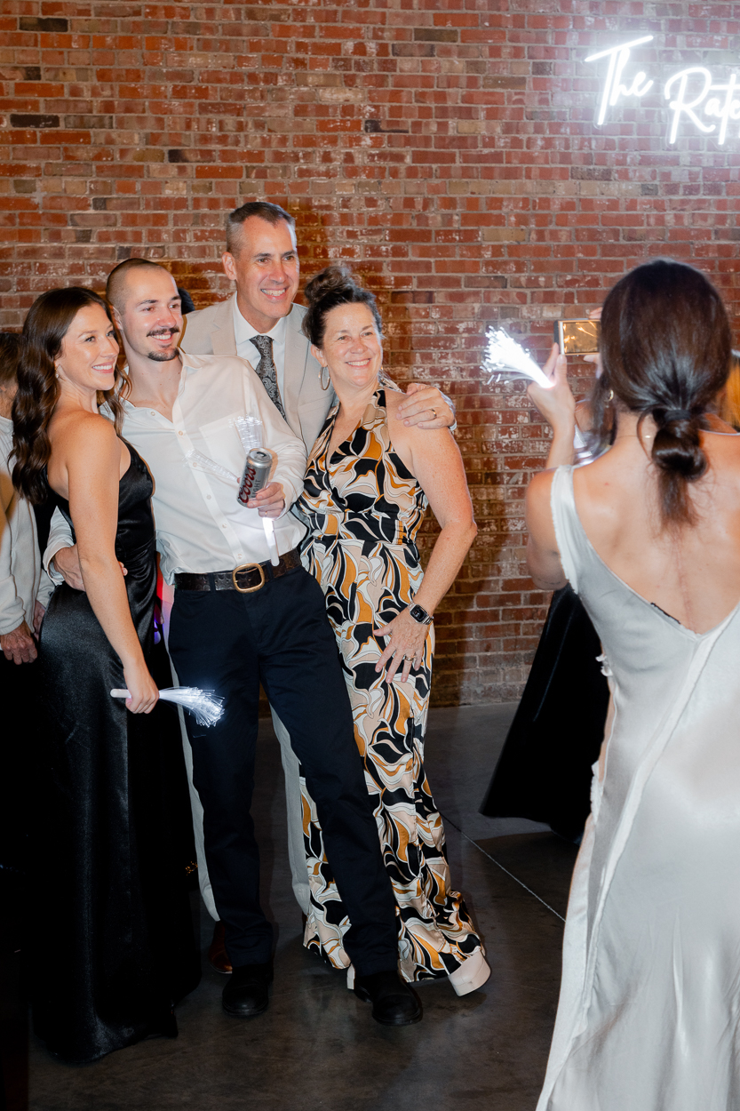 Family members posing for a photo against the exposed brick wall at The Atrium on Tenth in Columbia, Missouri.