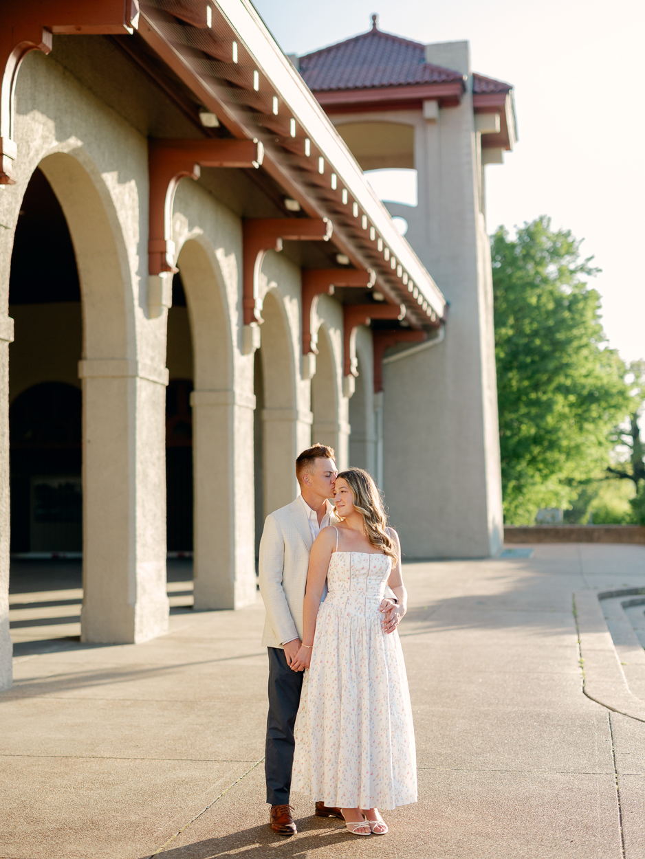 St. Louis engagement photographer captures couple sharing a kiss on the steps of the World's Fair Pavilion in Forest Park at golden hour.
