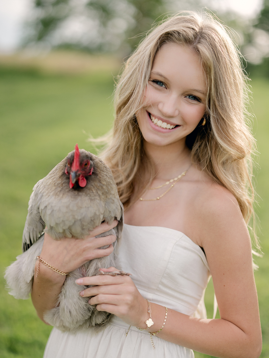 Smiling teen girl holding a gray chicken, farm family portrait Columbia MO.