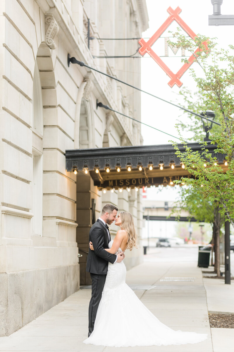 Bride and groom embracing outside the Missouri Athletic Club in downtown St. Louis, wedding photography by Emily Broadbent.
